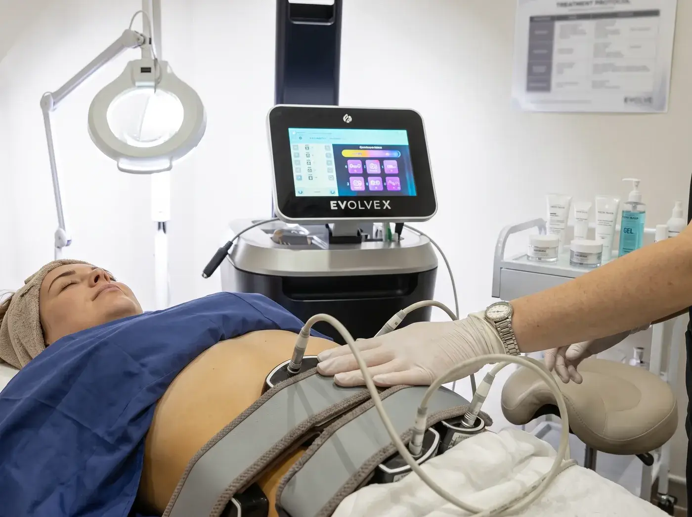 A Well Labs+ provider adjusting an EvolveX Transform applicator on a client's abdomen during a non-surgical body contouring session