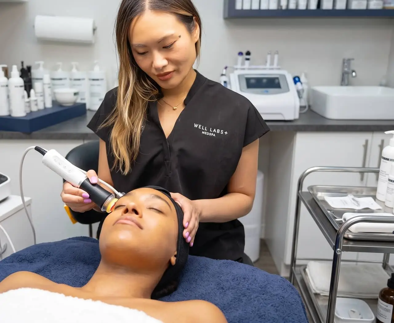 A Well Labs+ provider performing a laser skin resurfacing treatment on a reclining client