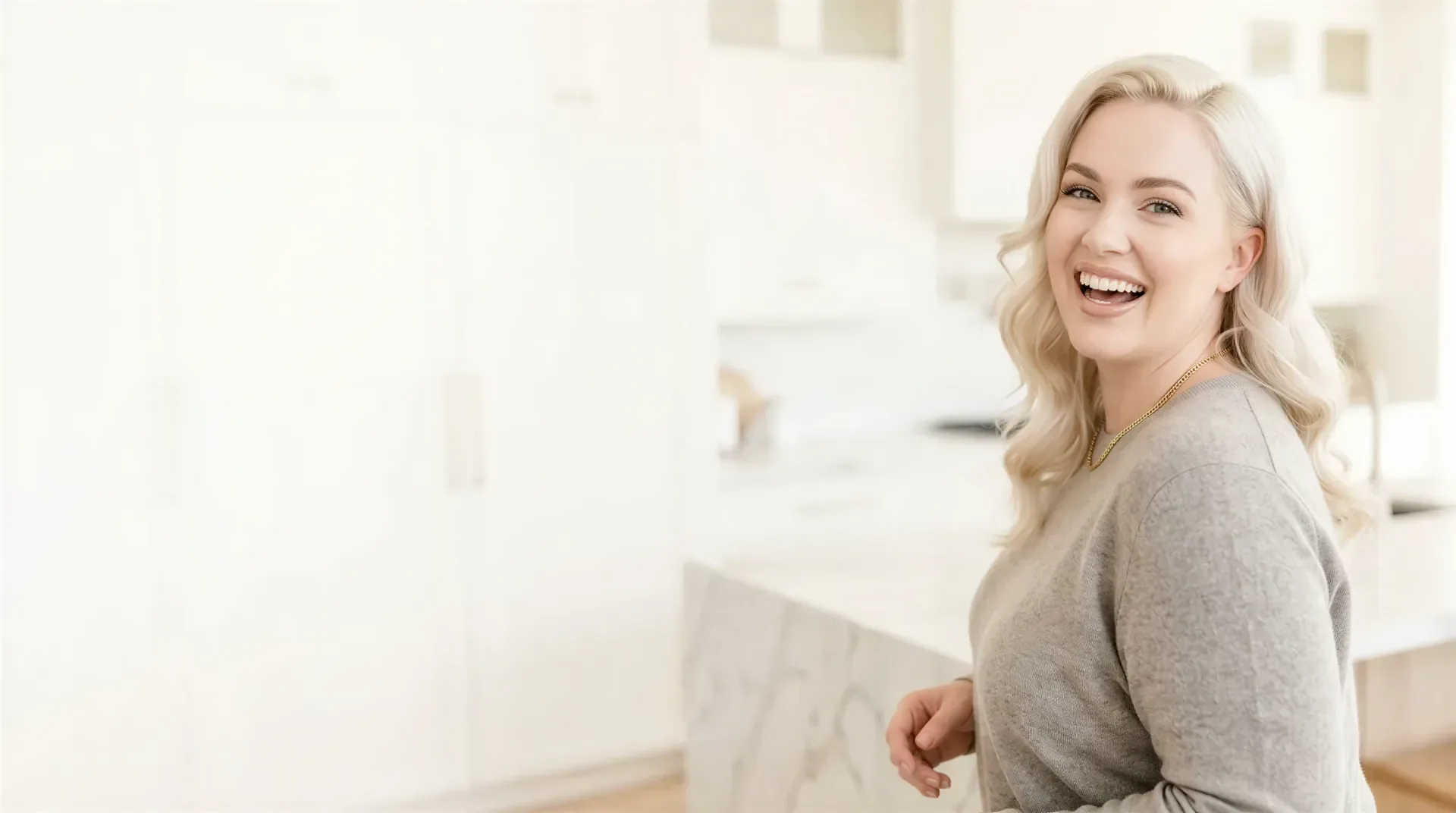 Smiling blonde woman in a bright modern kitchen, evoking a non-surgical body contouring plan at a Dallas medical spa