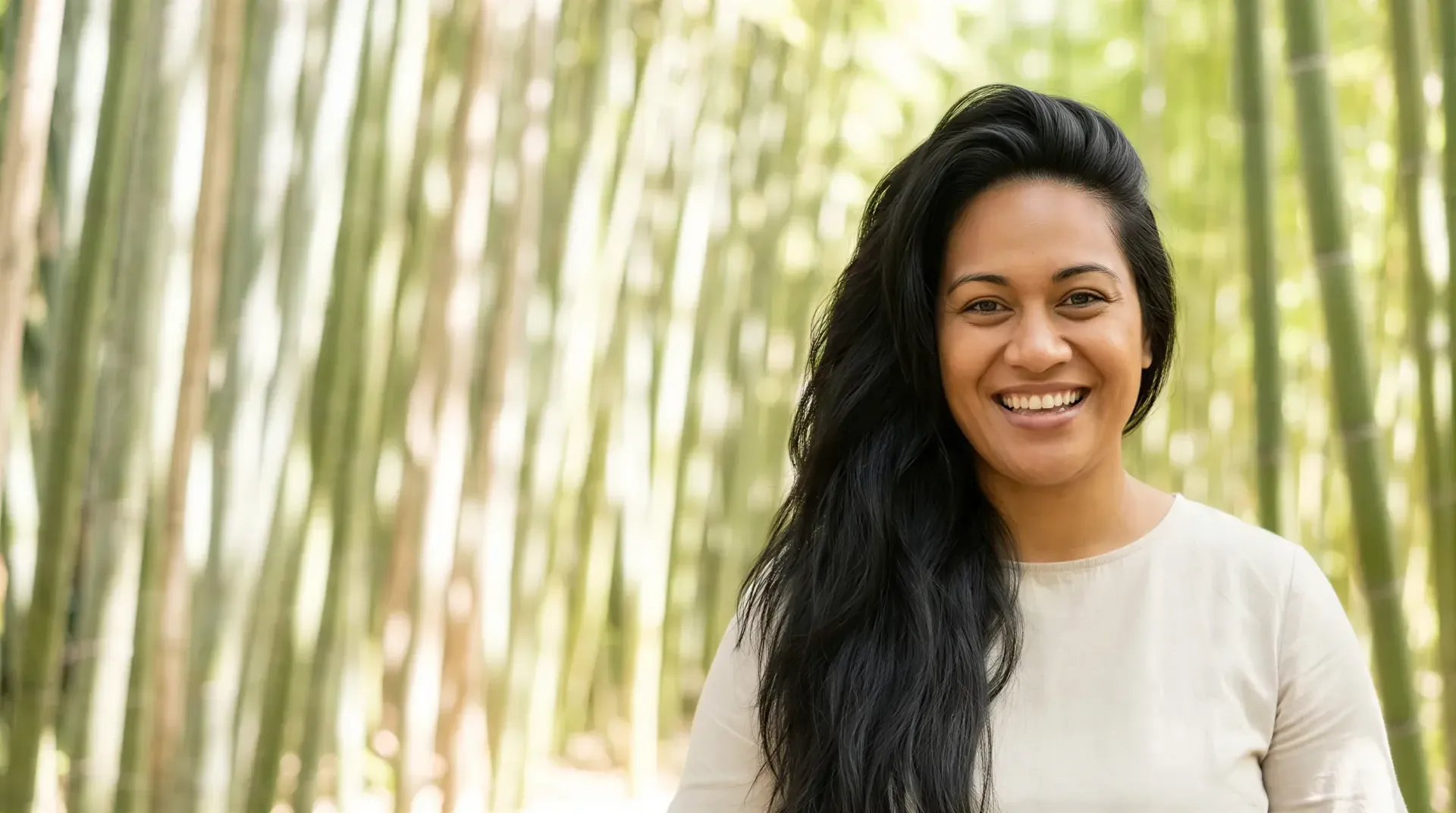 Smiling woman with radiant, even skin among sunlit bamboo, evoking a brighter Hollywood Spectra laser facial glow in Dallas