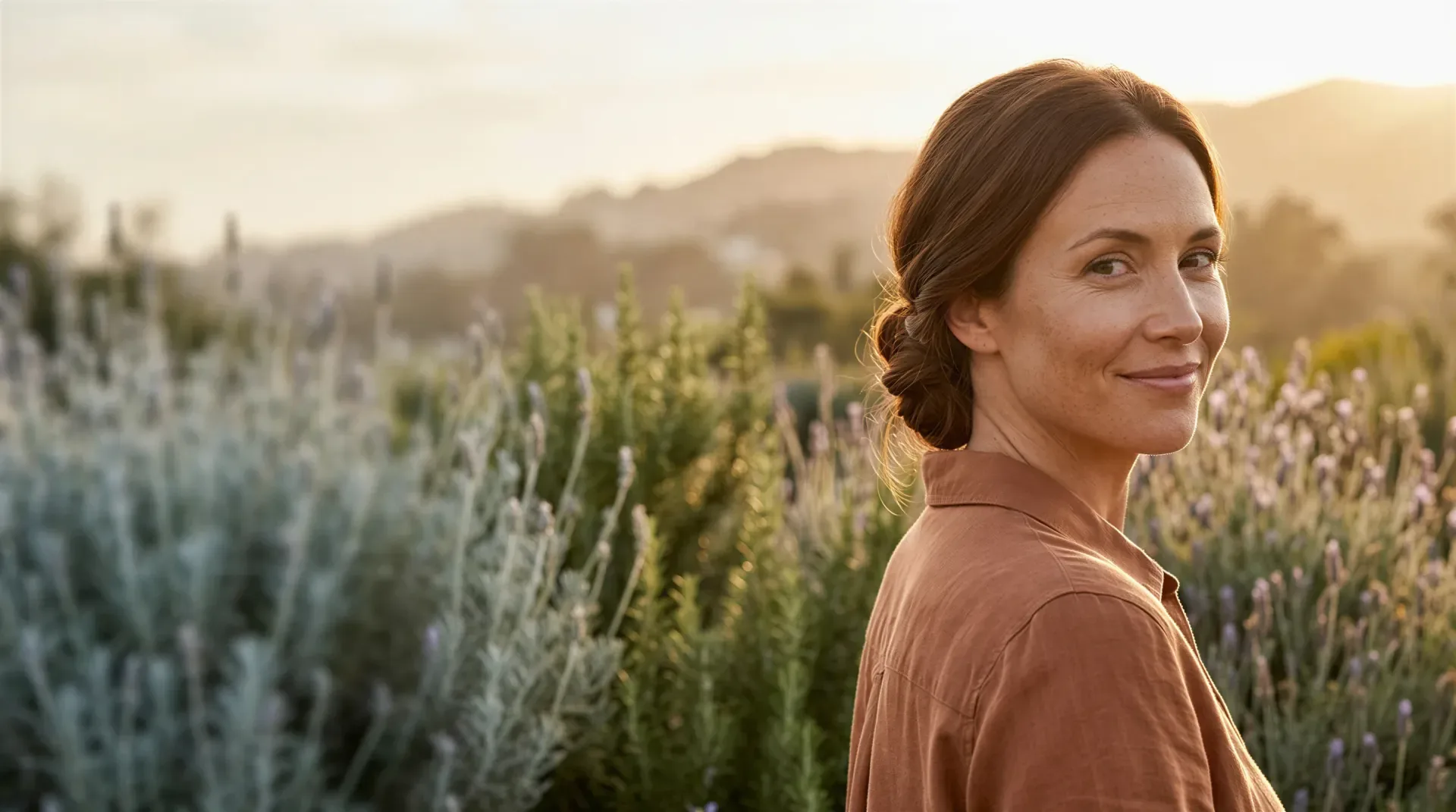 Woman smiling softly in a sunlit lavender field at golden hour