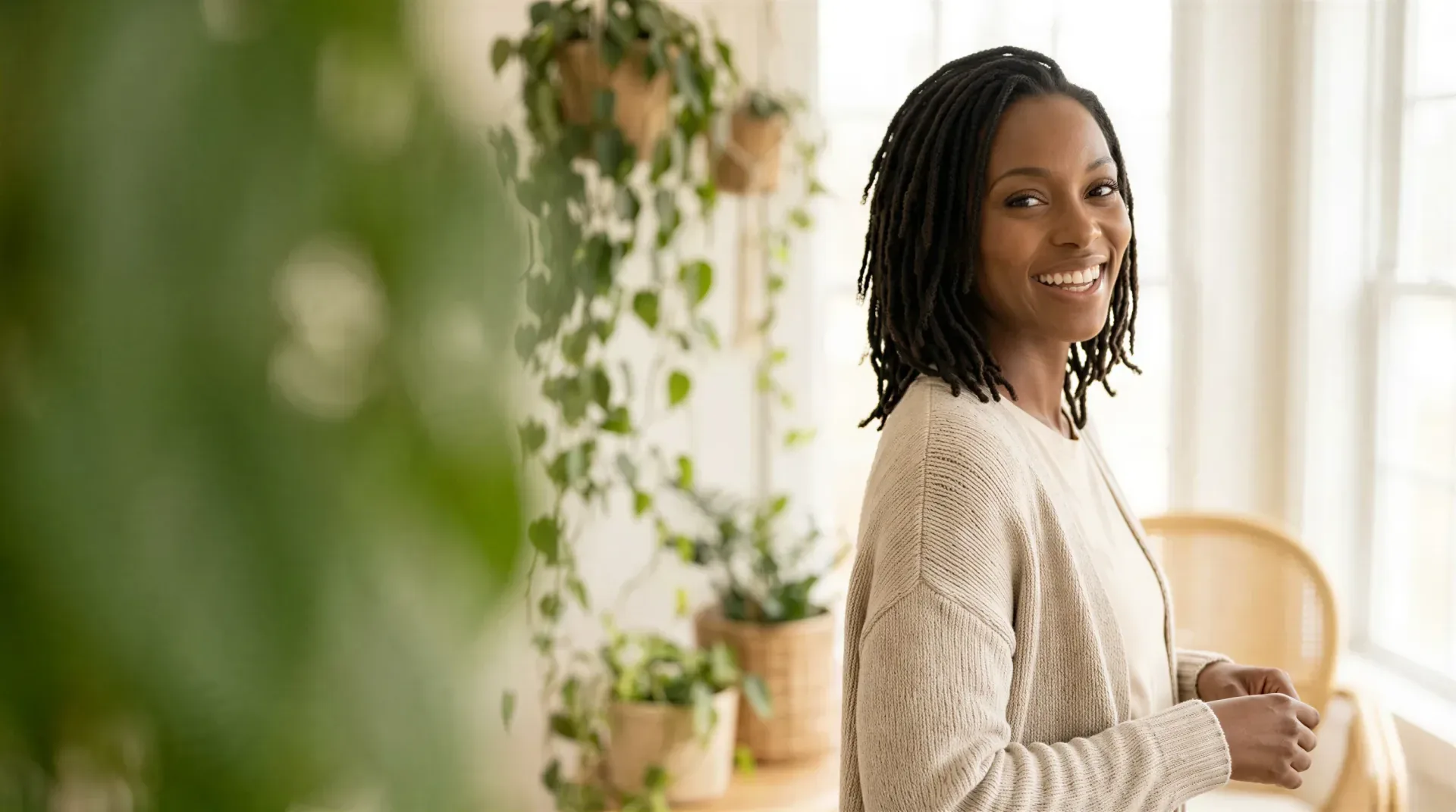 Smiling woman with clear, healthy skin in a bright, plant-filled room, evoking a provider-chosen medical-grade skincare routine in Dallas
