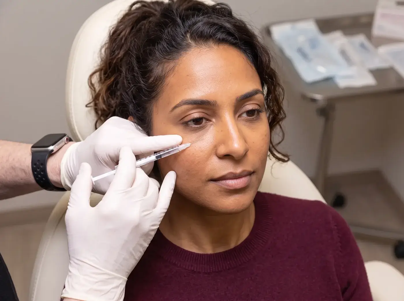 A gloved Well Labs+ provider injecting dermal filler along a client’s cheek for natural facial balancing