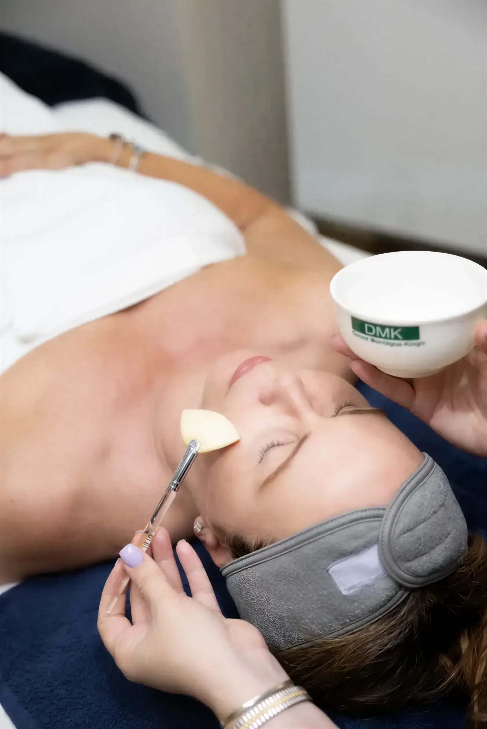 A Well Labs+ esthetician applying a DMK enzyme therapy treatment to a client's face