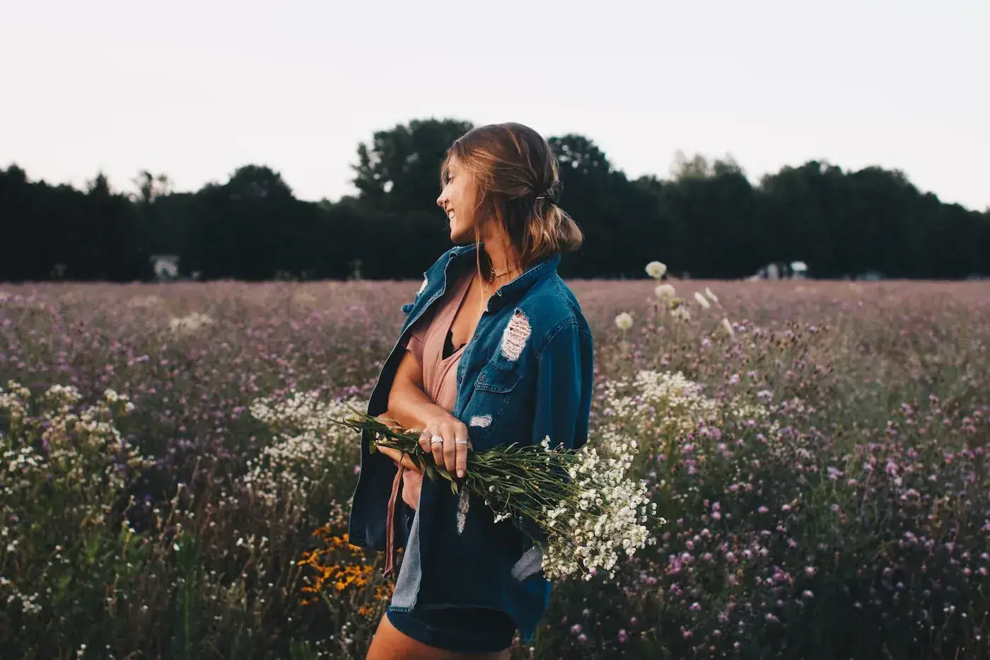 A woman smiling in a wildflower field at golden hour