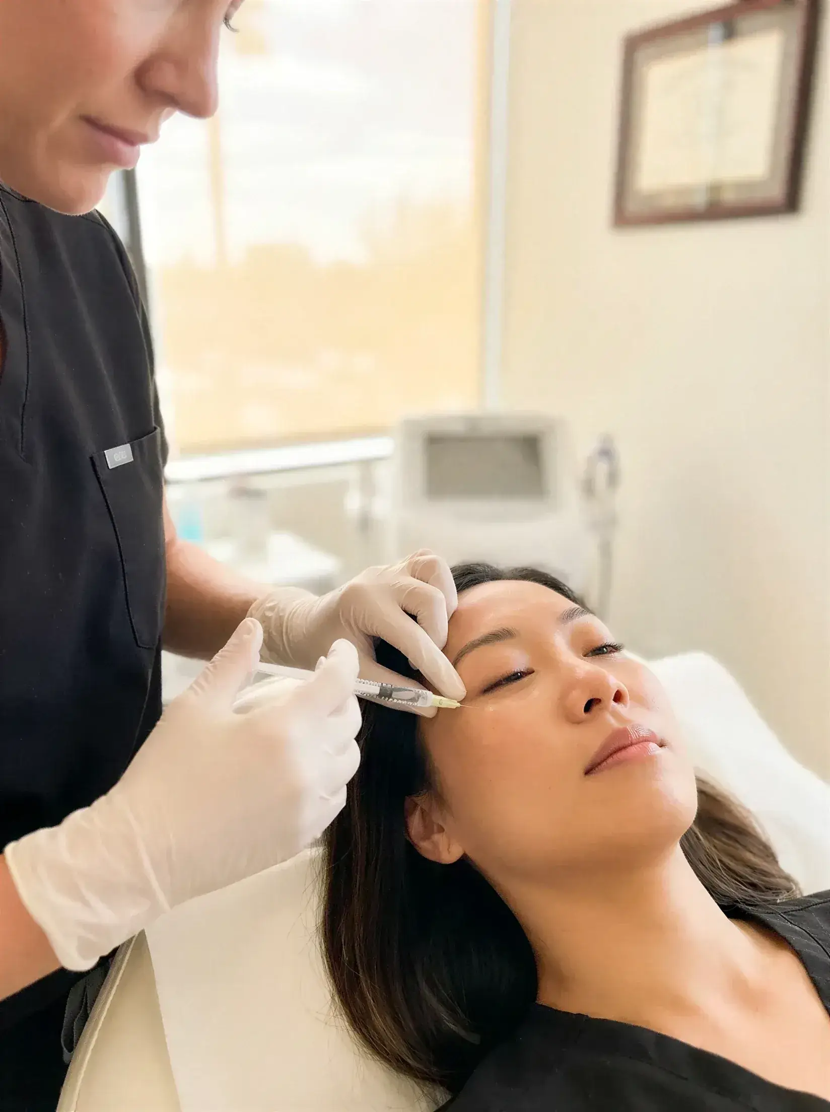 A gloved provider injecting RHA dermal filler into a client's under-eye area with a fine cannula