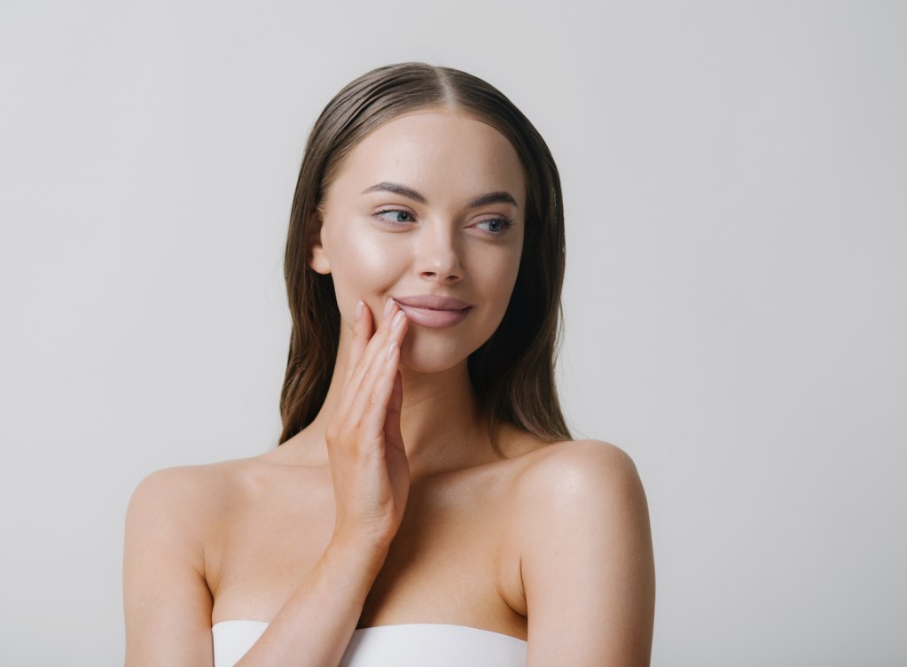 RF Microneedling blog Natural beauty woman with heands touching face long brunette hair beautiful neck and shoulders